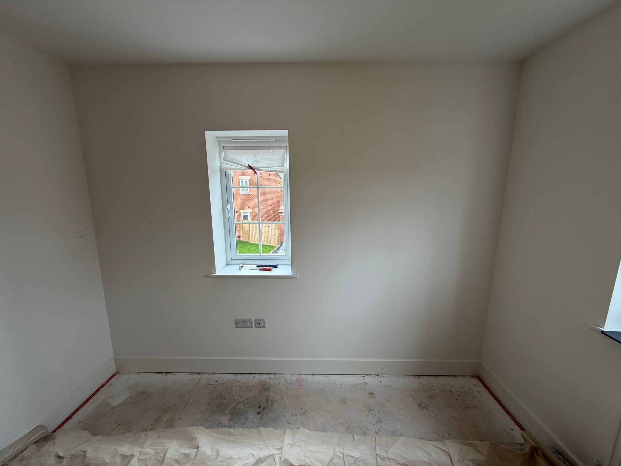 The Barrow upon Soar bedroom before: a bare wall with a single window and the floor covered for fitting
