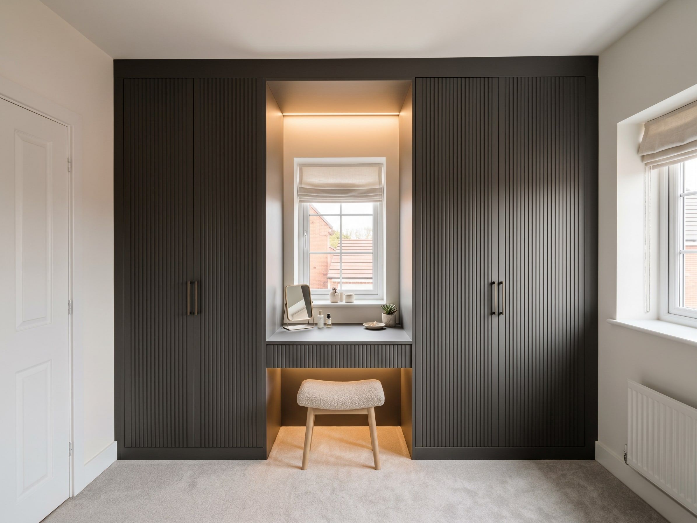 Floor-to-ceiling Stockholm fluted wardrobes in dark grey supermatt with black handles, bridging over a lit dressing space under the window, Barrow upon Soar
