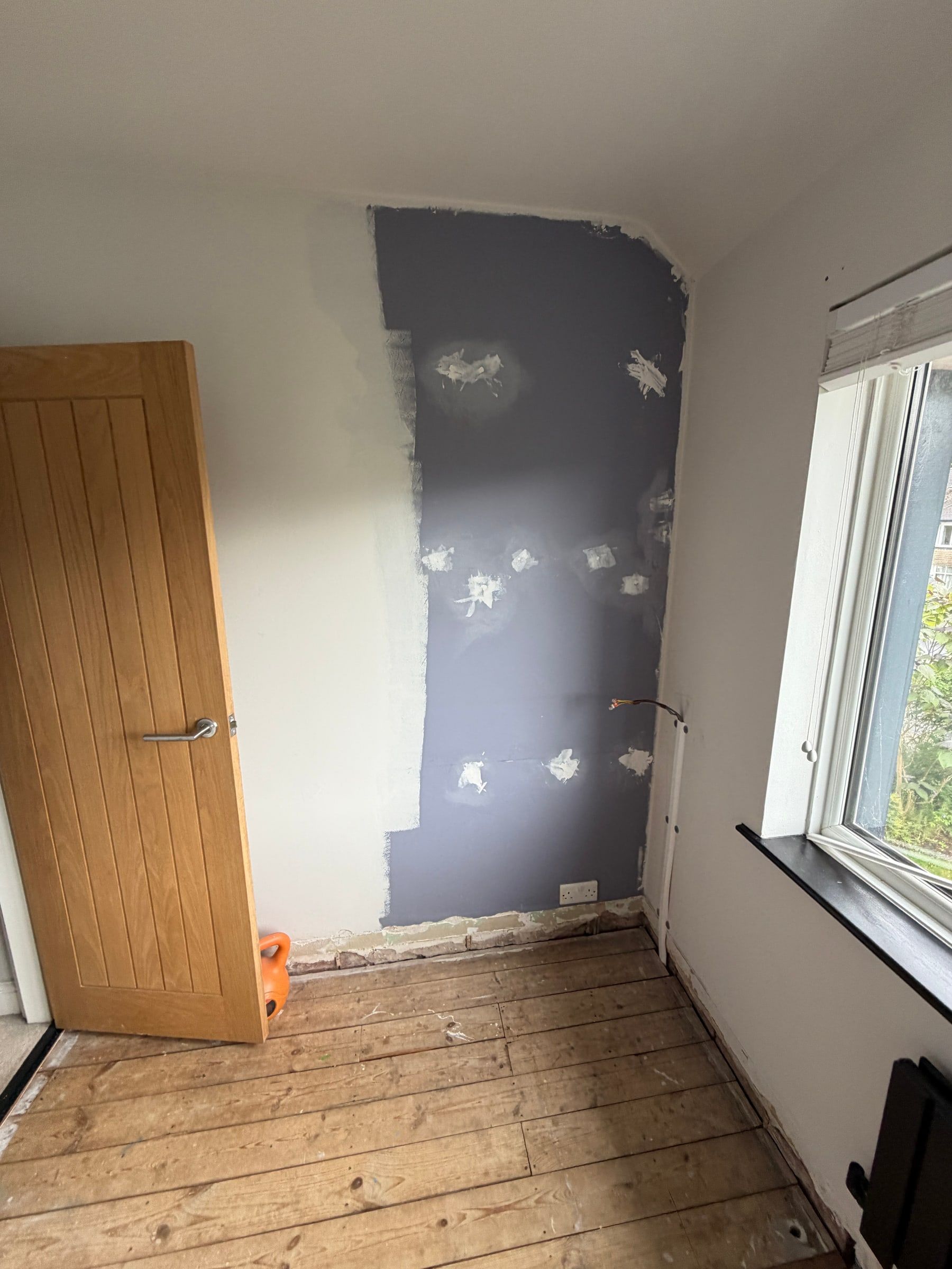The Bramcote room before, looking back towards the door, with bare floorboards and patched plaster