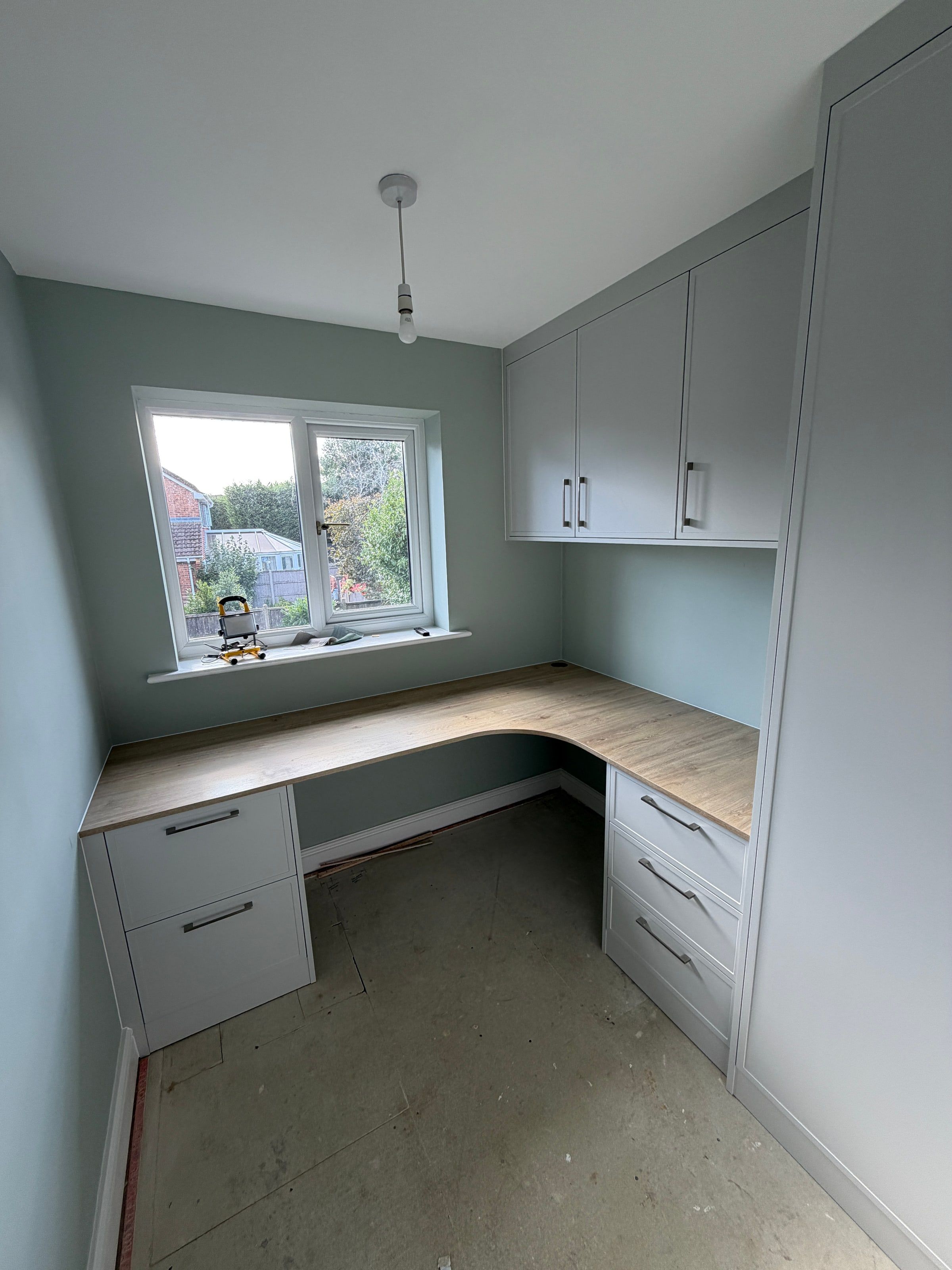 The Hinckley home office as fitted, before the carpet went down: L-shaped oak-effect desk under the window, drawers either side and light grey Alpine Shaker wall cupboards