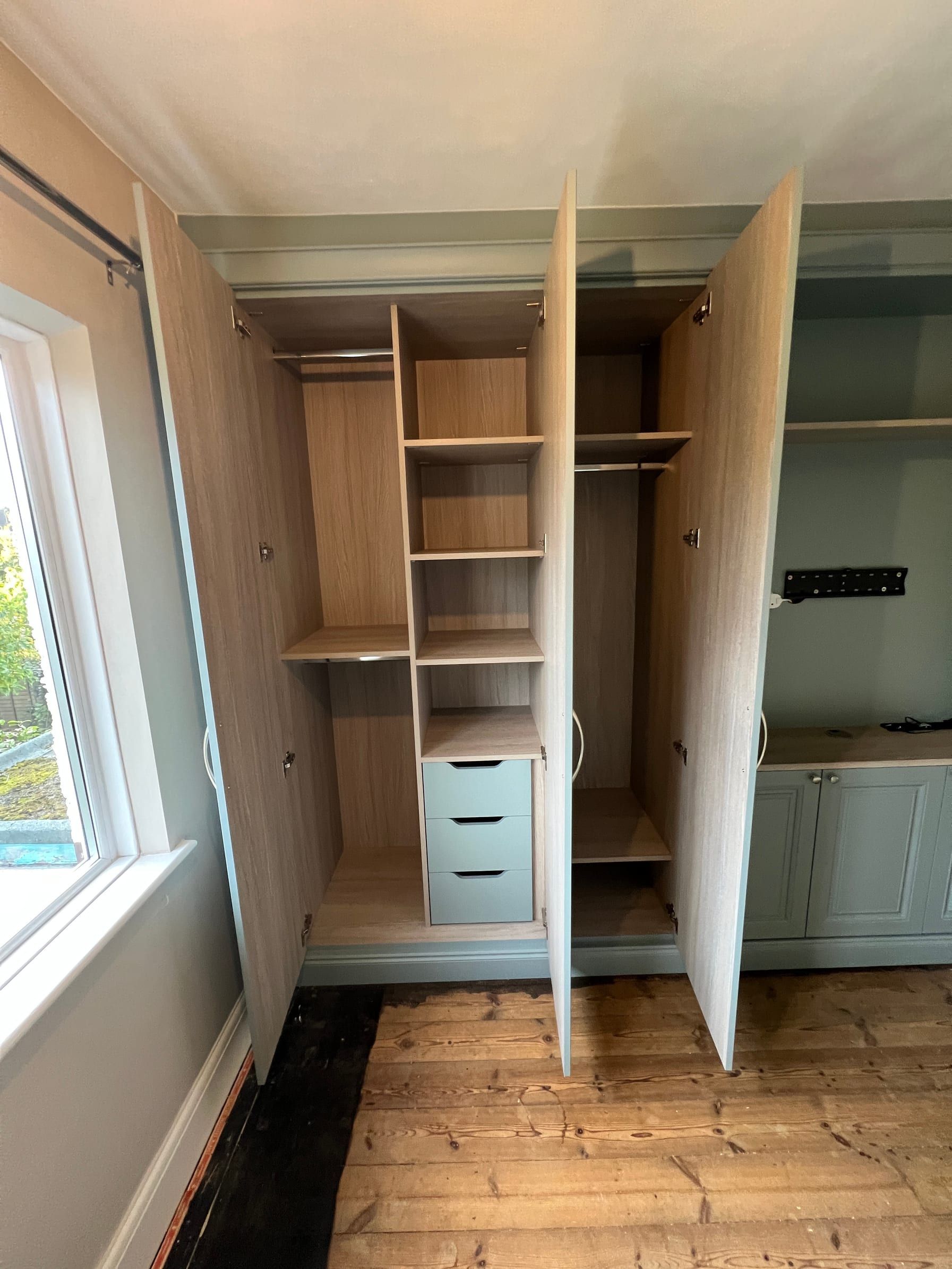 A Loughborough wardrobe by the window open to show shelves, drawers and hanging space