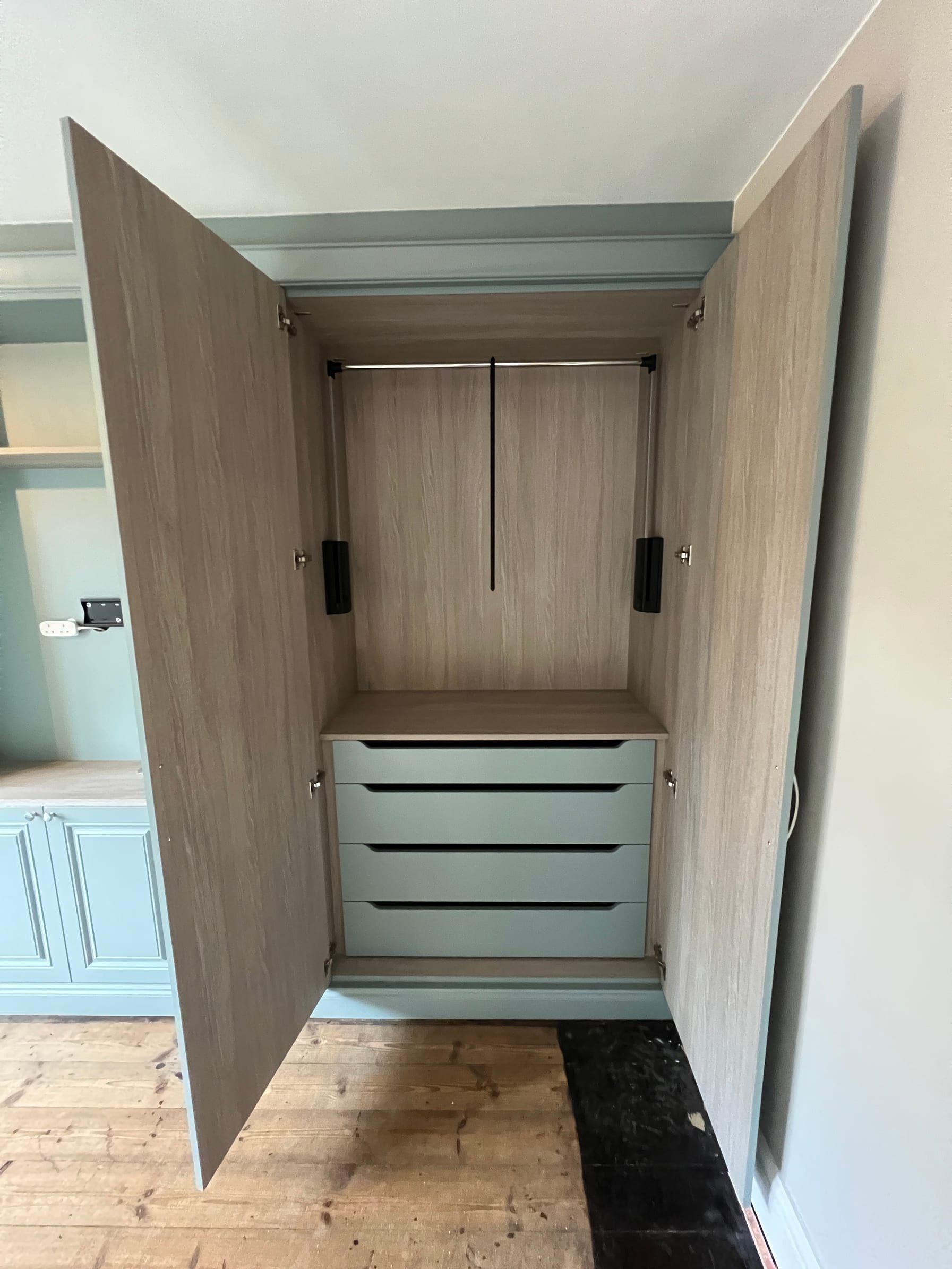 A Loughborough wardrobe open to show a pull-down hanging rail above a bank of drawers