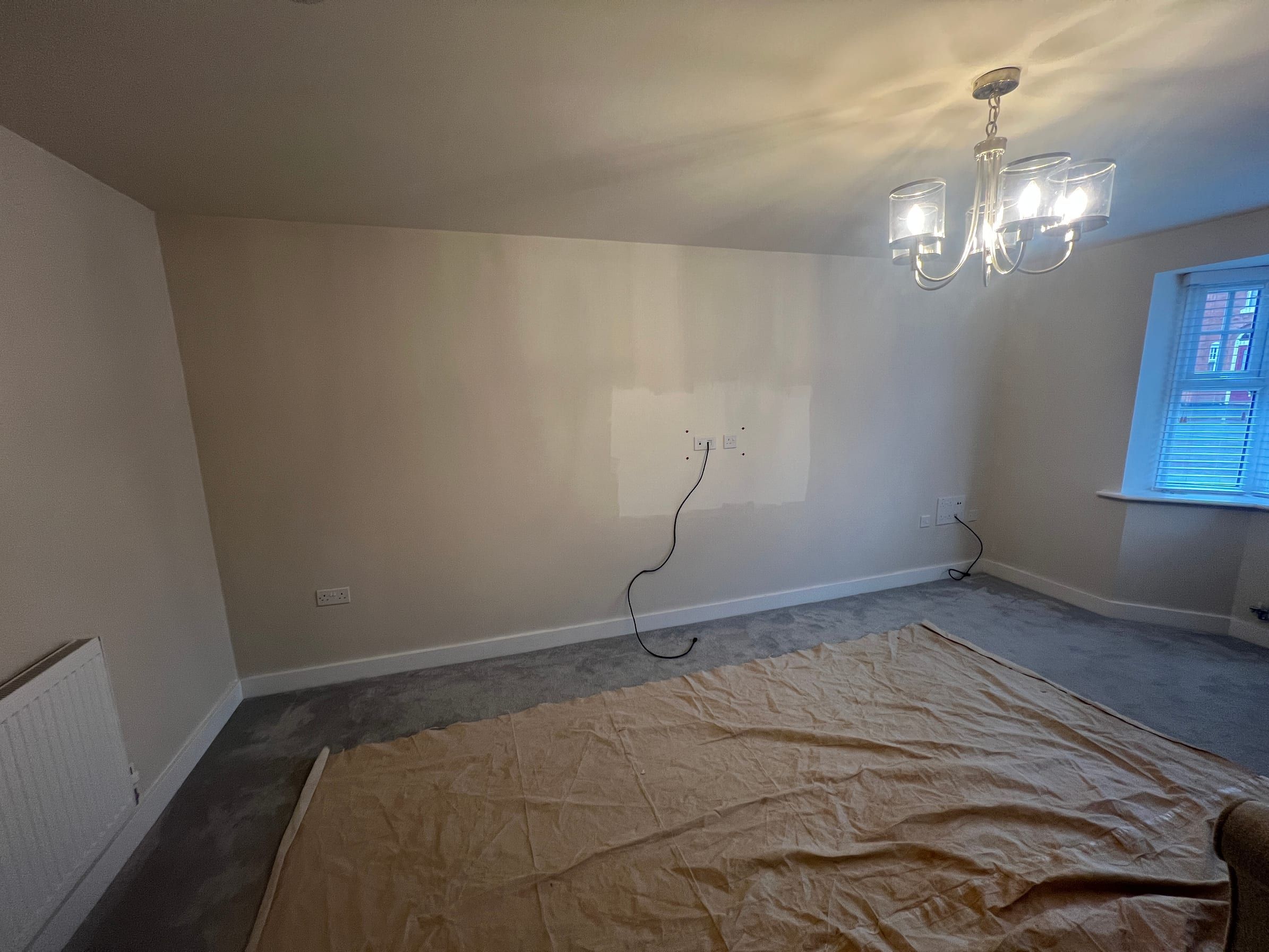 The Ratcliffe on the Wreake living room before: a bare wall with cables where the television would go