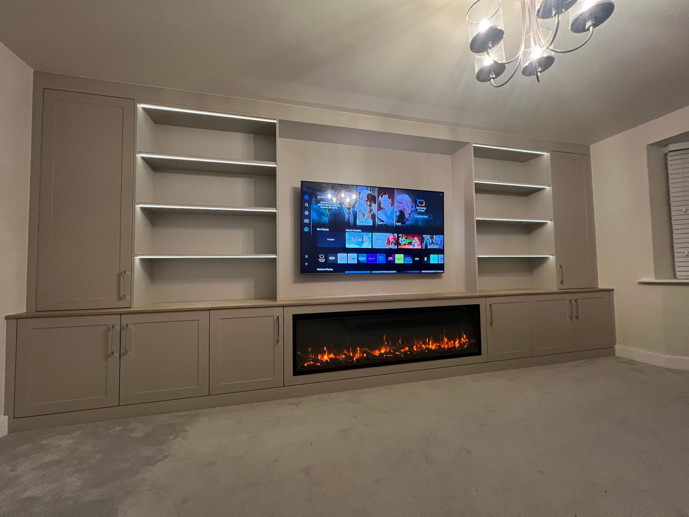 The Ratcliffe on the Wreake media wall as fitted: tall cupboards at each end, open shelves either side of the television and the fire set into the low cupboards
